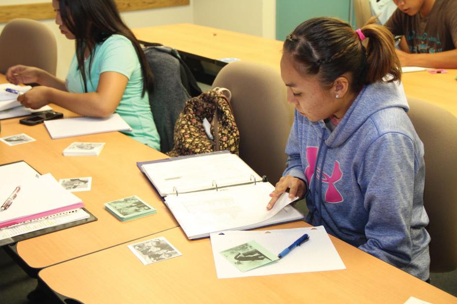 Students sitting at desk looking through notebooks